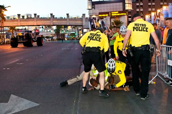 Las Vegas Metropolitan Police take down a spectator as he tried to run into the street to get a closer look at the monster trucks as the parade of 11 Champions of Advance Auto Parts Monster Jam SM World Finals travels down Las Vegas Boulevard Thursday night, March 21, 2013.